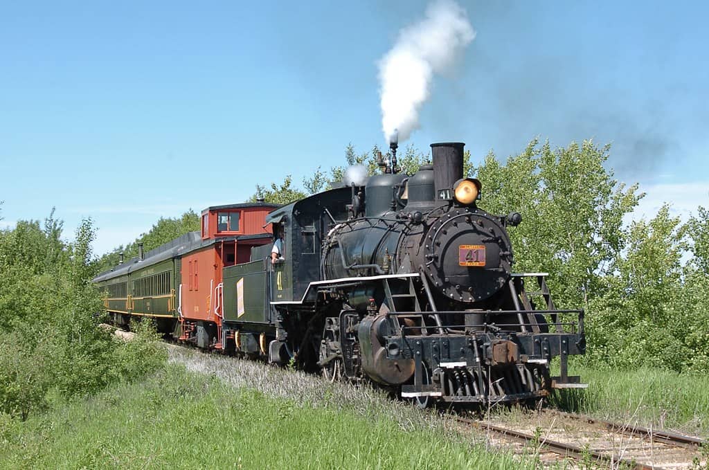 This trip lasts five (5) hours, travels to the Village of Big Valley and is one of the five premium styles of trips being offered by Alberta Prairie Railway in 2024. Dine on barbecued side ribs, chuckwagon beans, baked potatoes, and tossed green salad. Includes complementary wine or beer with the meal. Live entertainment on the train, plus time to do some exploring in the village including Jimmy Jock Boardwalk, restored station, the cars and household artifacts at McAlister Motors community museum, and the world-class Big Valley Tool Museum. Train robbery by the Reynolds Raiders horse-mounted outlaw gang likely.